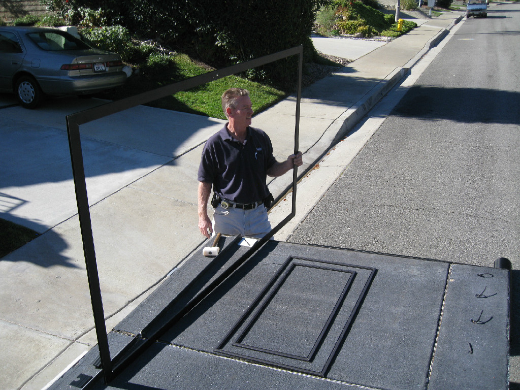 Fred Stickles holding a large window screen frame at a residential job